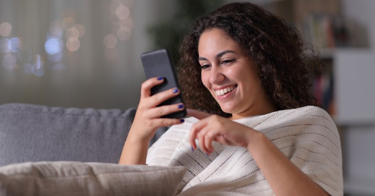 young woman sitting on couch using mobile device