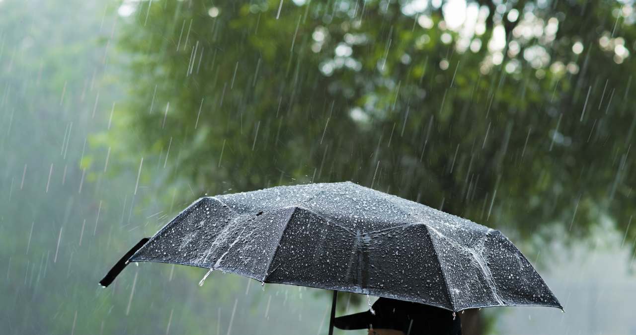 Man with umbrella standing in heavy rain
