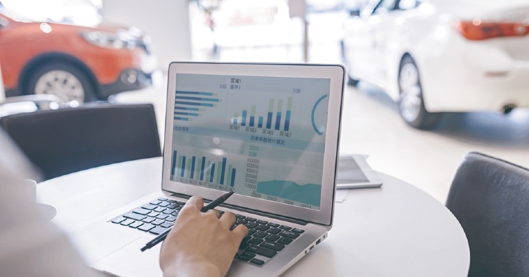 person using laptop showing metrics in car dealership