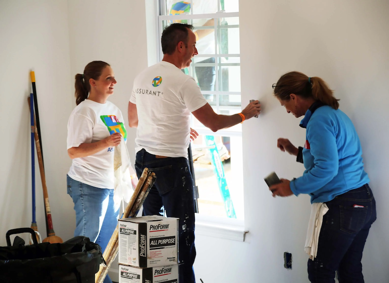 A group of Assurant employees volunteering and building a house