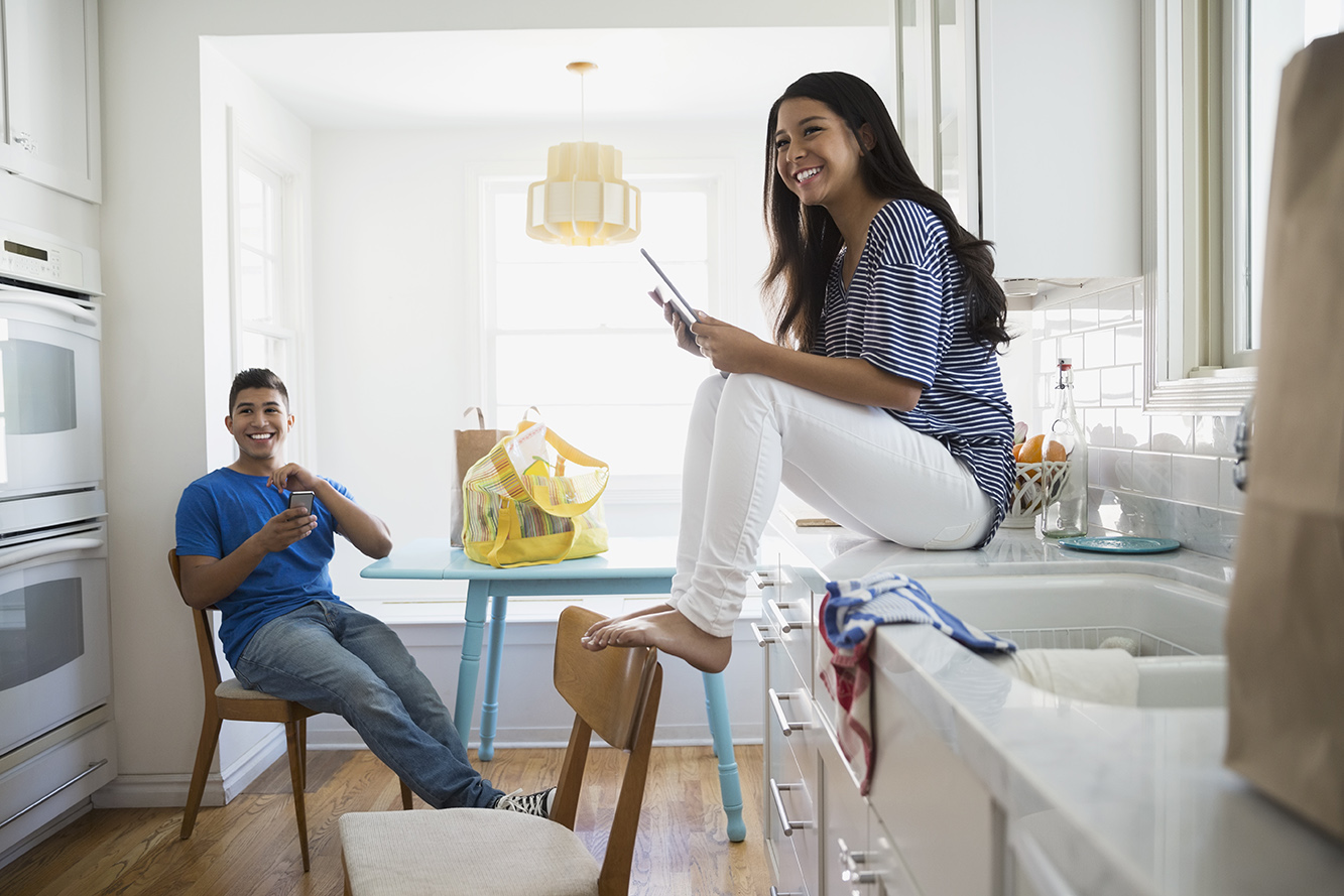 couple in white kitchen with devices