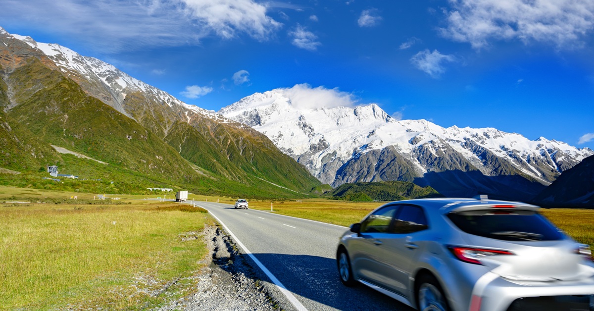 cars on a road with snowy mountains in the background