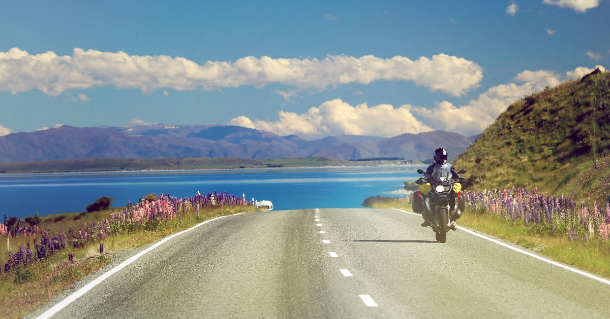 a person riding a motorcycle down a road next to a lake